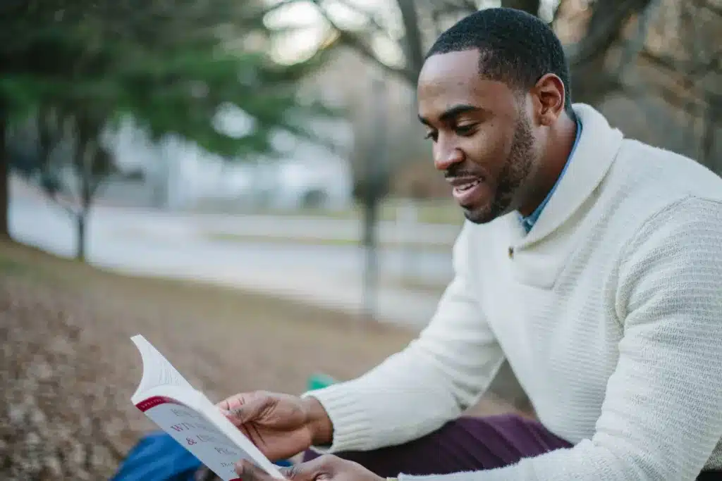 رجل اسمر البشرة يقوم بقراءة كتاب مع ابتسامة، بناء العادات